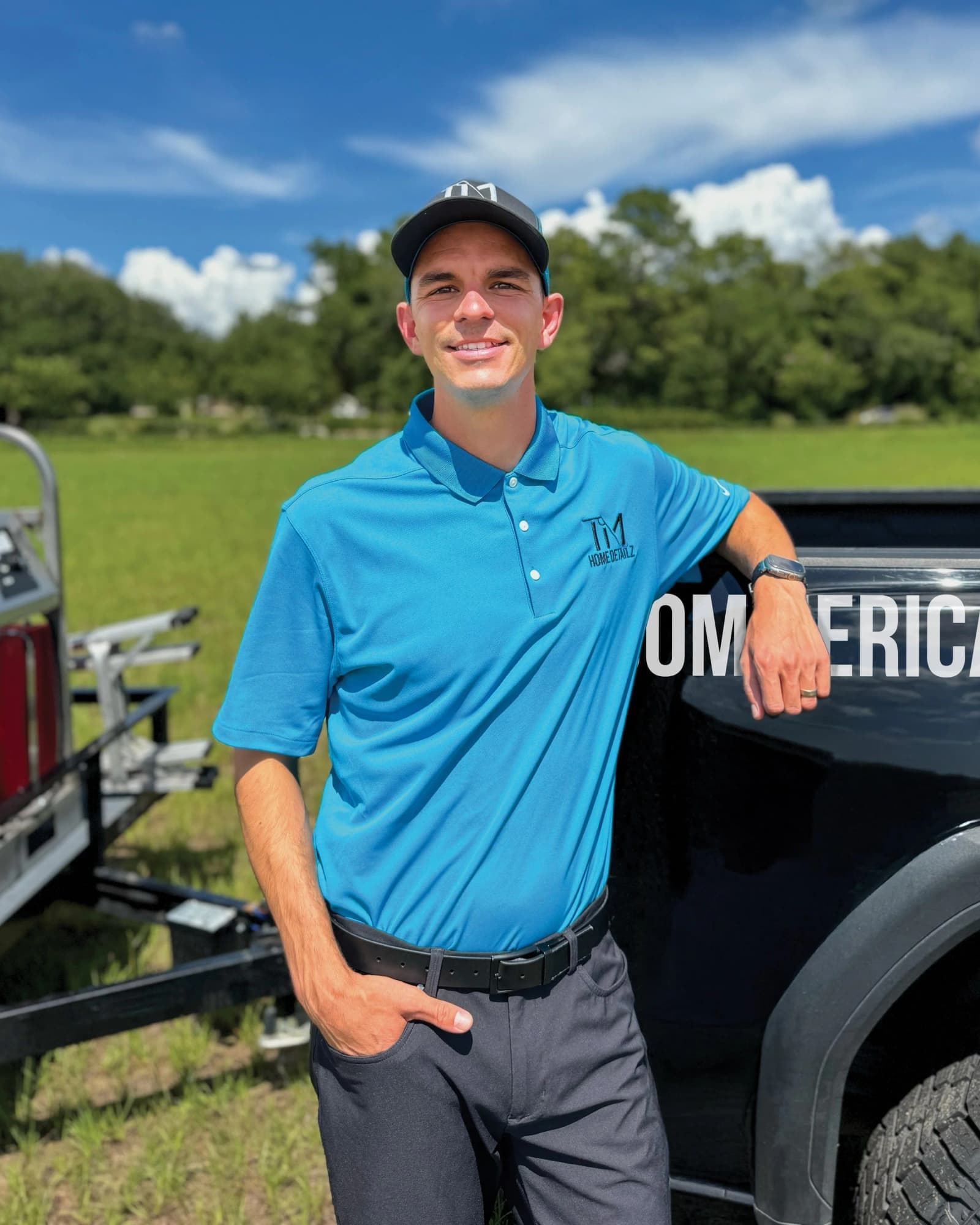 Travis Moss standing beside his truck and pressure washing trailer